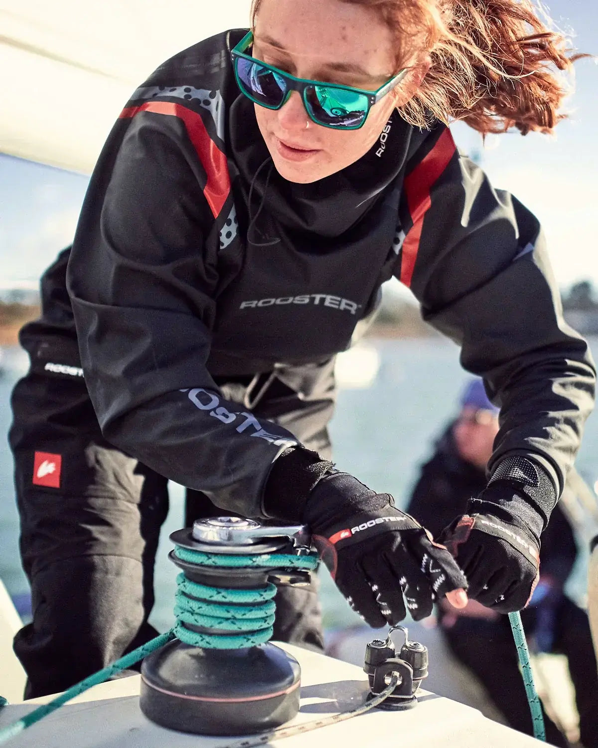 Femme utilisant des Gants Pro Race 2 de Rooster sur un voilier, mettant en avant la performance technique en navigation.
