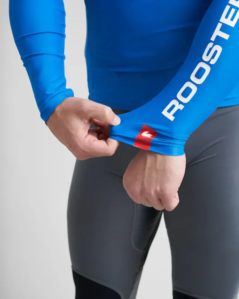 Homme ajustant les manches de son Rash Top-Long Sleeved Rooster en lycra spandex, offrant protection anti-UV.