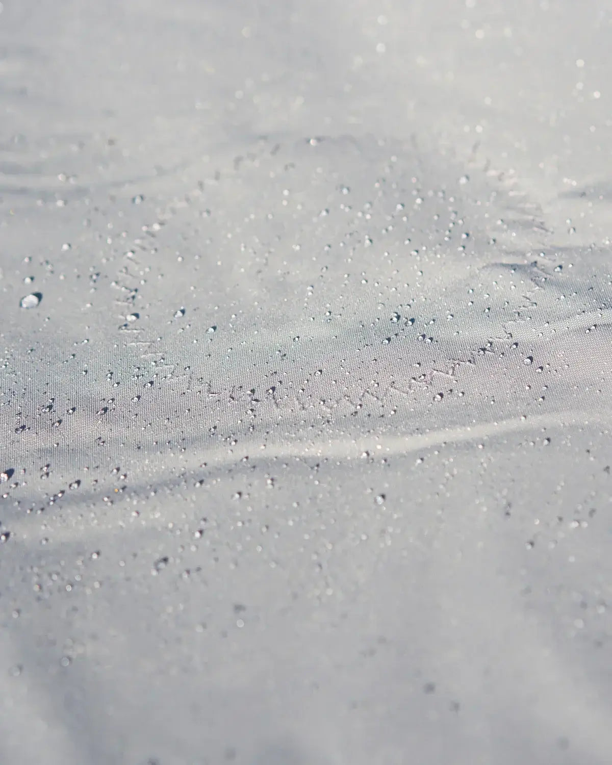 Surface étanche d'un Taud du dessus ILCA avec gouttes d'eau, illustrant ses propriétés imperméables et respirantes.
