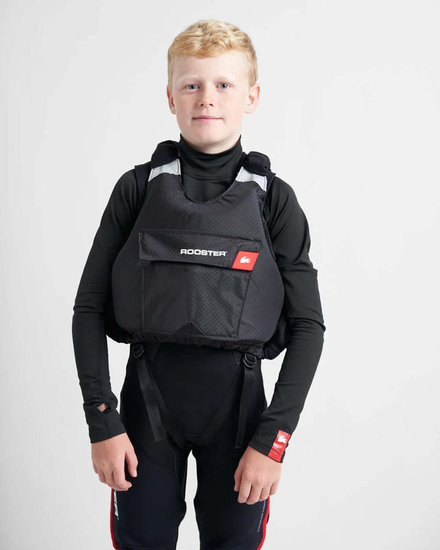 Gilet de sauvetage Rooster® Diamond Junior porté par un jeune garçon en tenue de voile et kayak.