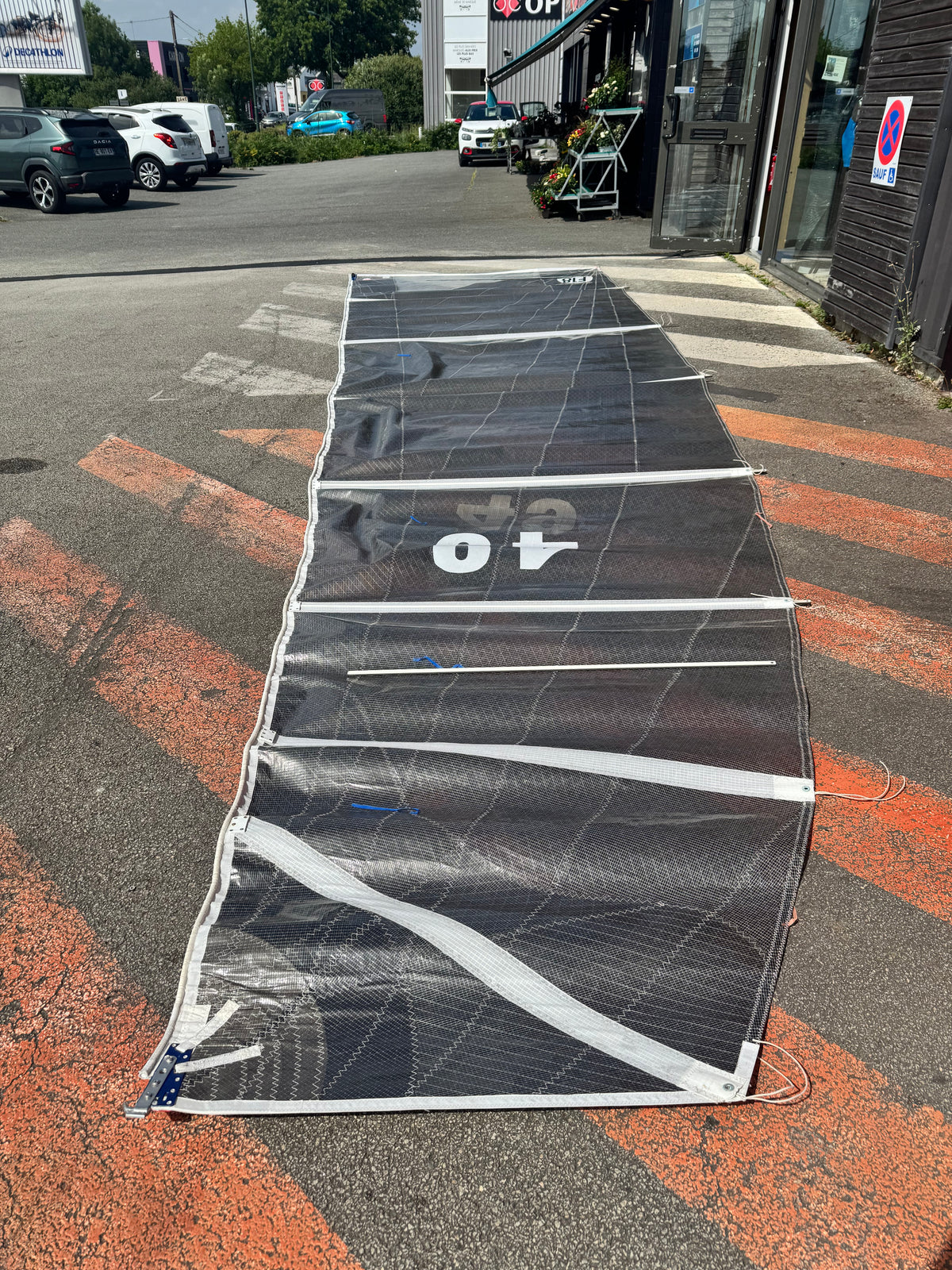 Voile F18 occasion état neuf étalée sur le sol, montrant des détails et des marques cosmétiques.