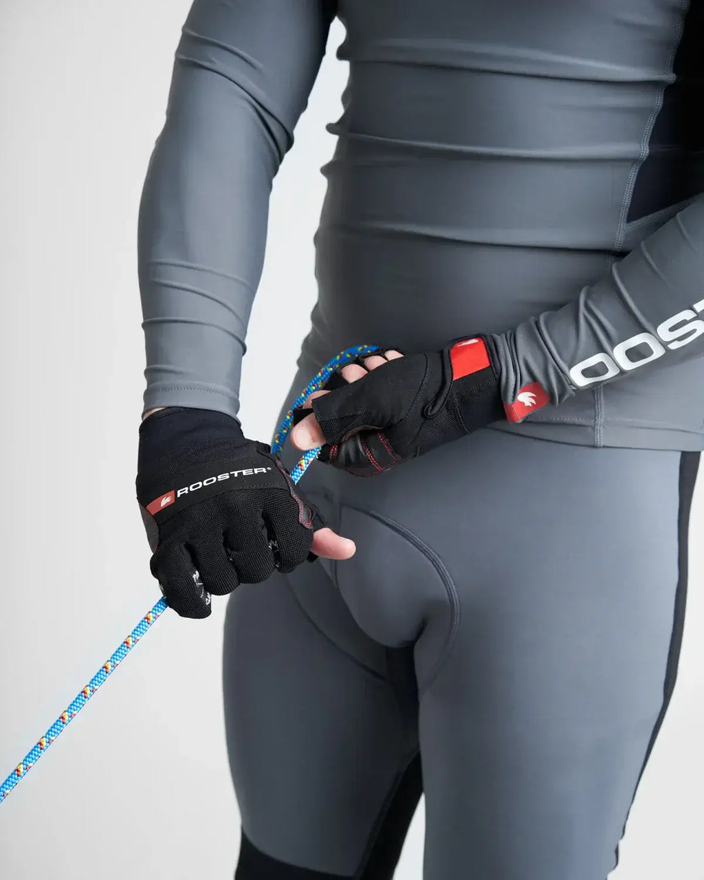Homme utilisant des Gants Pro Race 5 de Rooster avec une corde lors d'une activité nautique.