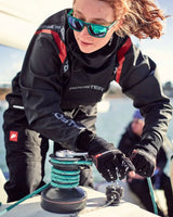 Femme utilisant des Gants Pro Race 2 de Rooster sur un voilier, mettant en avant la performance technique en navigation.