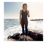 Long John Thermaflex 1.5mm femme portés par une femme sur des rochers au bord de la mer.