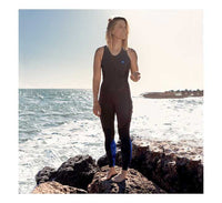 Long John Thermaflex 1.5mm femme portés par une femme sur des rochers au bord de la mer.