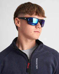 Lunettes sport polarisées sur un jeune homme portant un pull noir, avec verre miroir bleu.