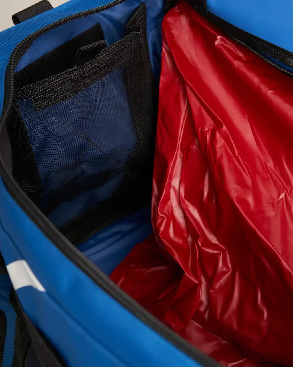 Intérieur du sac multifonctions 60L étanche avec compartiment rouge et poches en filet.