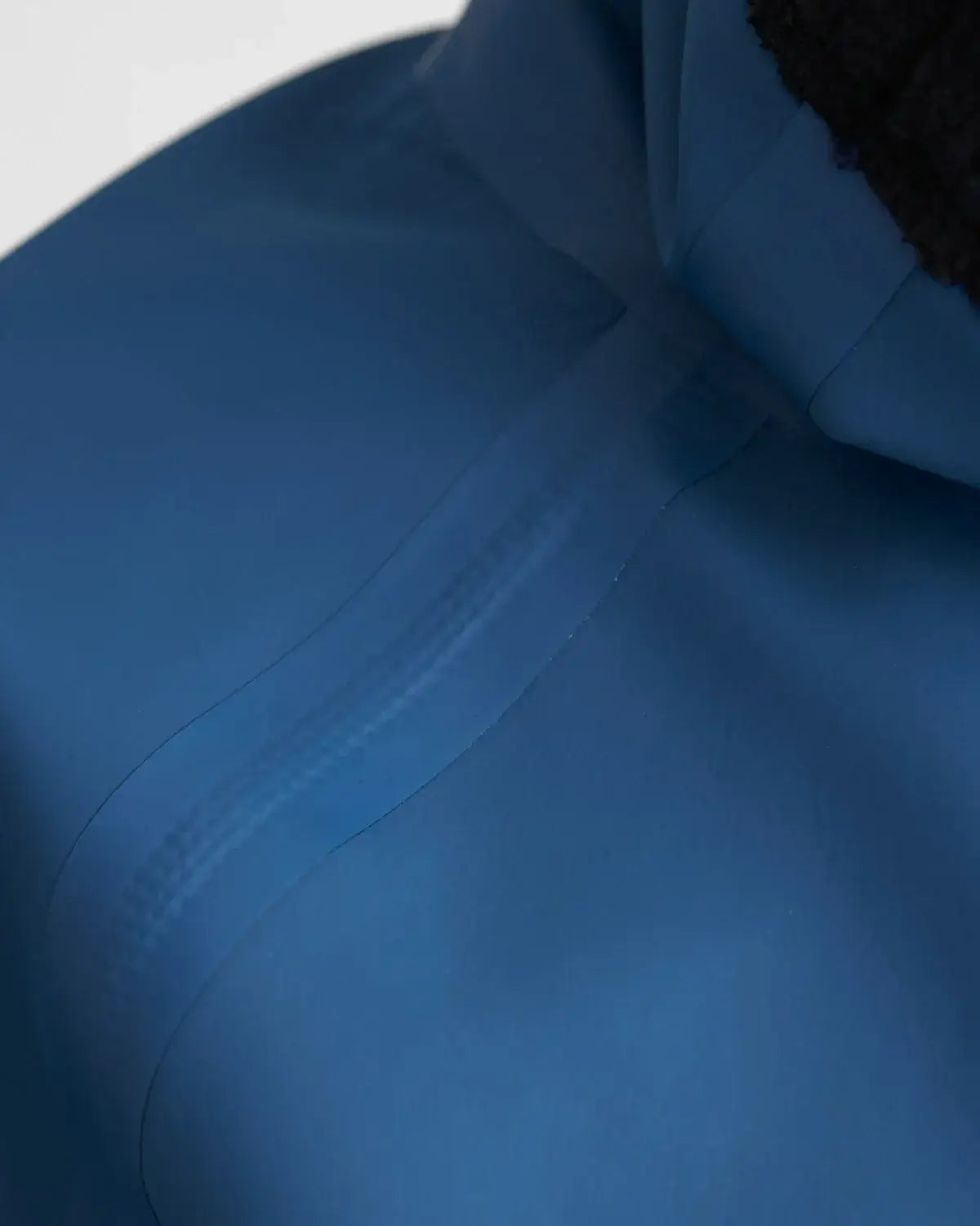 Détail du haut Top Pro Aquafleece Women montrant une couture étanche sur un tissu imperméable.